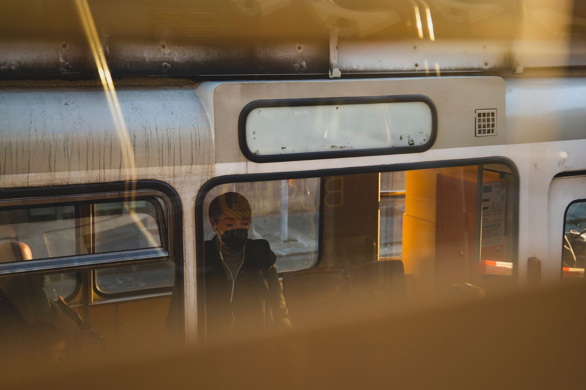 View of a masked commuter on public transport in Vienna, captured during sunset.
