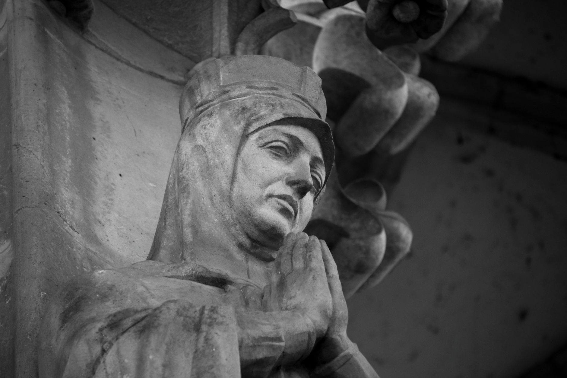 Grayscale image of a historic sculpture depicting a praying saint's serene expression.