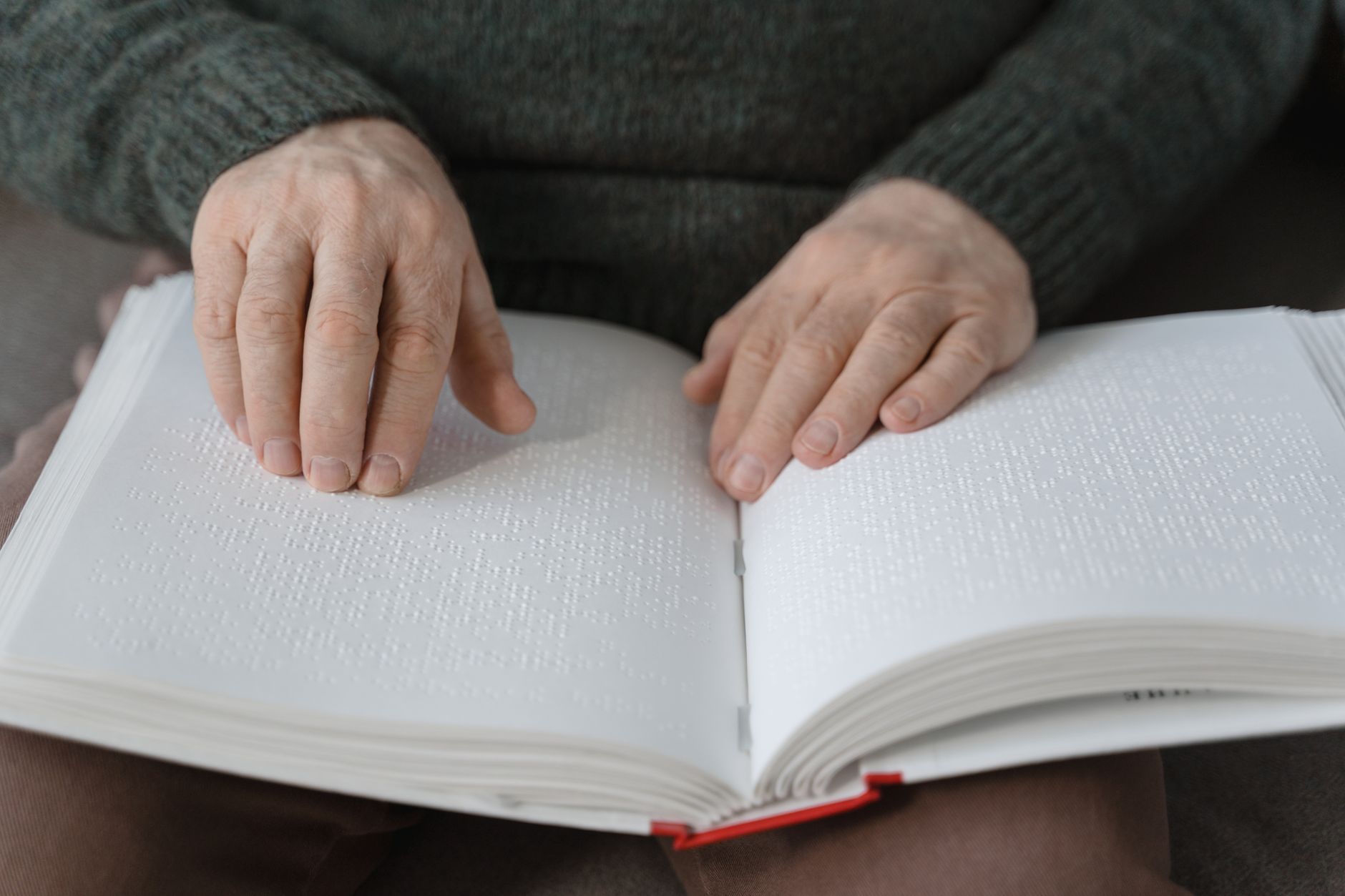A person reading a braille book, highlighting tactile learning and accessibility.