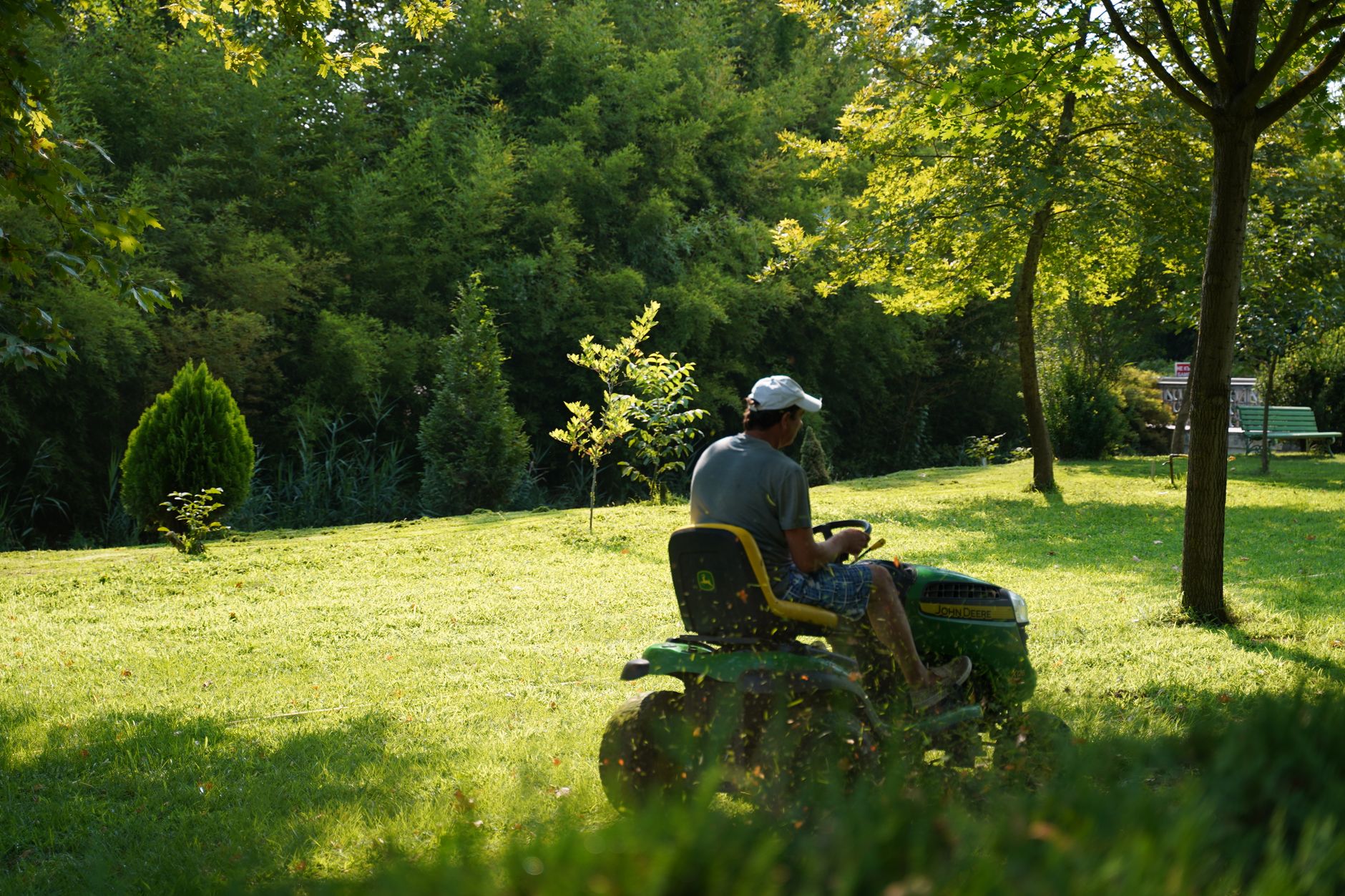 Un homme utilisant une tondeuse à gazon par une journée ensoleillée dans un jardin verdoyant